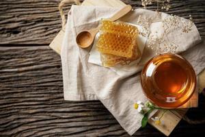 honung bi i burk och vaxkaka med honung dipper och blomma på trä- tabell, bi Produkter förbi organisk naturlig Ingredienser begrepp foto