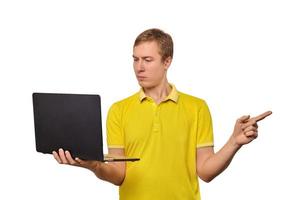 förbryllad ung man med bärbar dator pekande med finger isolerat på vit bakgrund, manlig förvirrad ansikte foto