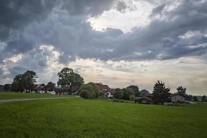 idyllisk landskap med grönt fält, väg, och traditionell tysk bondgårdar. foto