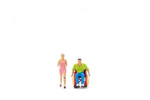 miniatyr- människor glad kvinna med ung Inaktiverad man i rullstol löpning foto