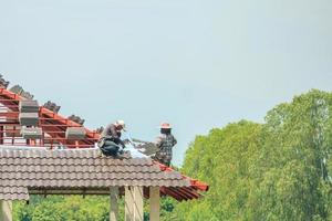 byggtäckare som installerar takpannor på husbyggarbetsplatsen foto