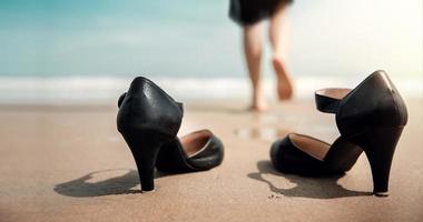 arbete liv balans begrepp. företag kvinna ta av henne arbetssätt skor och lämna den på de sand strand för promenad in i de hav. sluta en jobb, kontor utflykt eller sommar semester. låg vinkel se foto