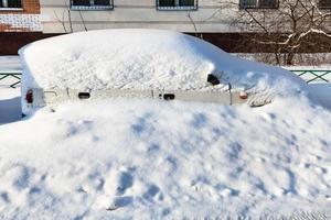 vit bil täckt med snö i parkering massa foto
