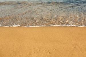 bakgrund med gyllene sand på de kust av de ö av Kreta. abstrakt yta med sand och klar hav vatten för text. foto