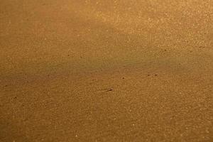 bakgrund med gyllene sand på de kust av de ö av Kreta. abstrakt yta med sand och klar hav vatten för text. foto