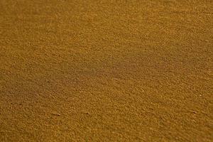 bakgrund med gyllene sand på de kust av de ö av Kreta. abstrakt yta med sand och klar hav vatten för text. foto
