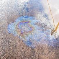 regnbågsskimrande filma av motor olja på asfalt trottoar foto