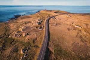 naturskön asfalt väg med gyllene fält på kustlinje i sommar på island foto