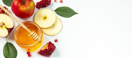 glad rosh hashanah. traditionell judisk semester nyår. äpplen, granatäpplen och honung på vit bakgrund. bannerformat, plats för text. foto