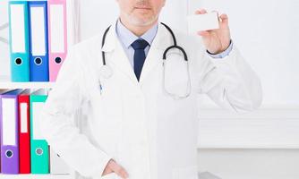 doktor håller visitkort på kliniken, sjukförsäkring, man i vit uniform. kopieringsutrymme foto
