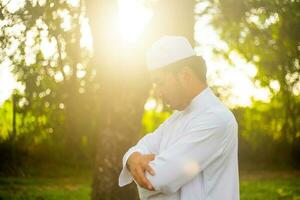 ung asiatisk muslim man bön- på solnedgång, ramadan festival begrepp foto