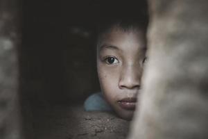 närbild fattig pojke kikar ut av en förfallen hus, begrepp av bistånd till de fattig, mänsklig rättigheter. foto
