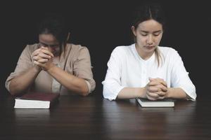 två kristen kvinnor sitta tillsammans och be på en trä- tabell med suddig öppen bibel sidor i deras hemrum. bön för bröder, tro, hoppas, kärlek, bön möte foto