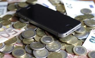 mobil betalning och smartphone - en mobil enhet som ligger på en hög med pengar foto
