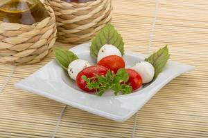 caprese sallad på tallriken och trä bakgrund foto