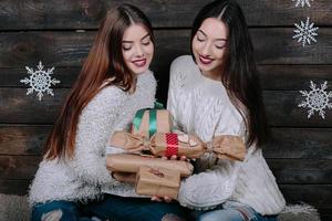 två skön flickor erbjudande gåvor till kamera foto