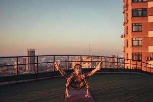 kvinna håller på med yoga på de tak av en skyskrapa i stor stad. foto