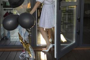 flicka i ballonger går in hus. brud är framställning för bröllop. vit klänning på flicka. vit skor. foto