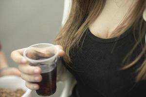 flicka innehar glas med dryck i henne hand. flicka dricka te utanför. foto