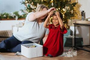 förälder och liten barn har roligt nära jul träd inomhus. foto