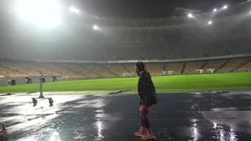 människor gå i för sporter på natt stadion i regnig väder foto
