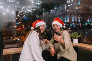 två ung flickor använder sig av smartphone på de Kafé. foto