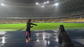 människor gå i för sporter på natt stadion i regnig väder foto