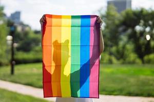 ung kvinna innehav ett HBTQ stolthet flagga i henne händer. foto