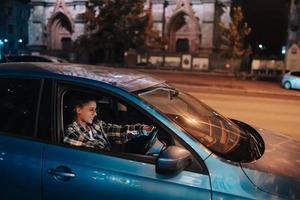 kvinna körning bil förbi natt i de stad foto