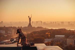 kvinna håller på med yoga på de tak av en skyskrapa i stor stad. foto