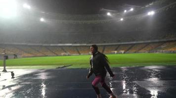 människor gå i för sporter på natt stadion i regnig väder foto