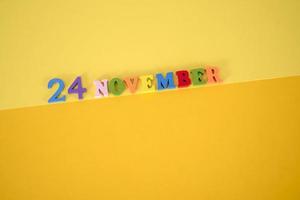 november 24 på en gul och papper bakgrund med trä- och flerfärgad brev med Plats för text. foto