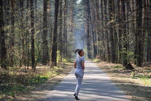 skön ung kvinna löpning i grön parkera på solig sommar dag foto