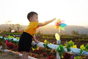 liten asiatisk pojke spelar med en väderkvarn på de lekplats. som är de dröm av barn handla om de begrepp av förnybar energi i miljö- teknik. foto