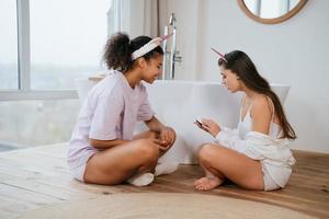 två flickor talande på de badrum golv foto