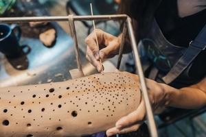 närbild se av kvinna händer försiktigt hantering en lera val i verkstad. foto