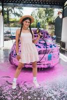 ung kvinna slang står i främre av en bil täckt i rosa skum foto
