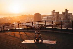 kvinna håller på med yoga på de tak av en skyskrapa i stor stad. foto