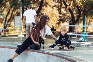 skön ung hipster mamma och liten son på de skatepark foto