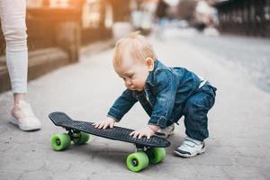 liten rolig pojke med skateboard på de gata foto