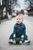 liten rolig pojke med skateboard på de gata foto