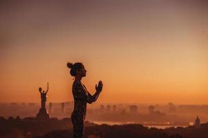 kvinna håller på med yoga på de tak av en skyskrapa i stor stad. foto