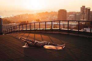 kvinna håller på med yoga på de tak av en skyskrapa i stor stad. foto