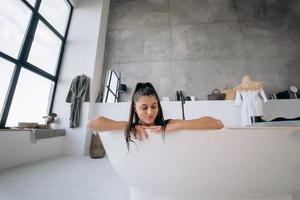avslappnad lady tar bad, njuter och avkopplande medan liggande i badkar foto