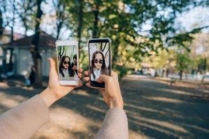 skön ung flicka innehar i henne händer två smartphones foto