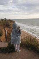 ung kvinna på kall höst havsstrand Framställ på kamera foto