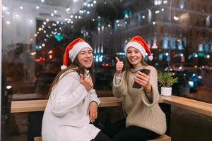 två ung flickor använder sig av smartphone på de Kafé. foto