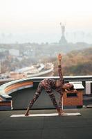 kvinna håller på med yoga på de tak av en skyskrapa i stor stad. foto