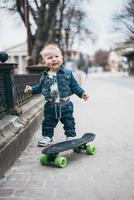 liten rolig pojke med skateboard på de gata foto