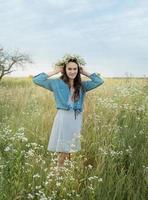 vacker flicka går på fältet på sommaren med vilda blommor. foto